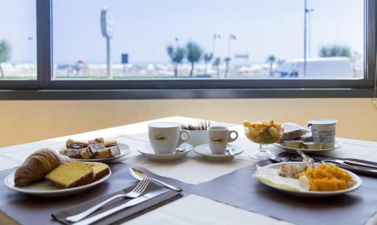 Colazione vista mare: dolci, frutta e caffè in un'atmosfera rilassante.