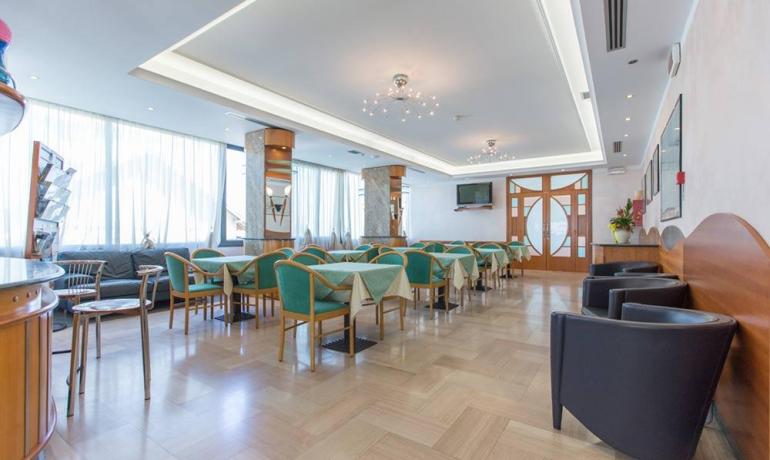 Elegante sala luminosa con sedie verdi, atmosfera accogliente e moderna.